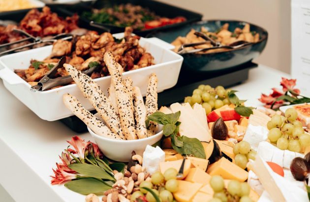 A mouth-watering assortment of cheeses, breadsticks, and fruits in a buffet setting. Perfect for catering events.